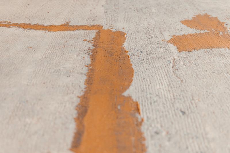 Close-up of repaired cracks on a newly sanded concrete floor, filled with epoxy mortar for a smooth, durable finish.